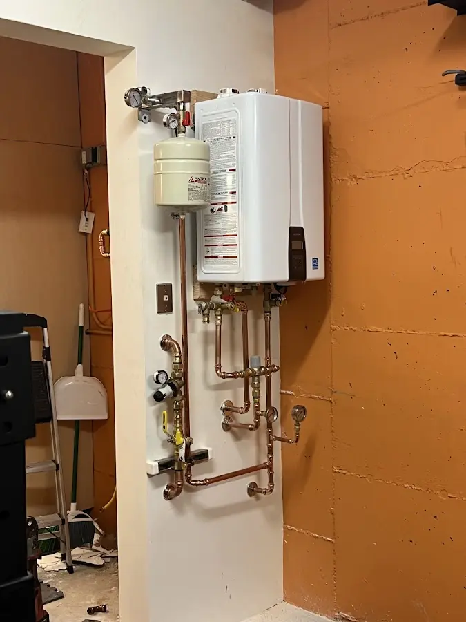 Plumbing technician inspecting water heater connections in De Pere